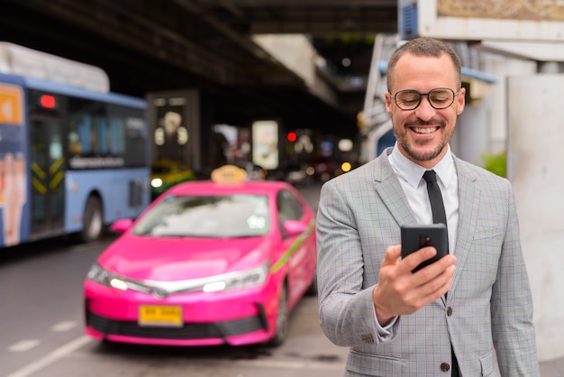 happy hispanic bald bearded businessman using phone taxi station 251136 31048